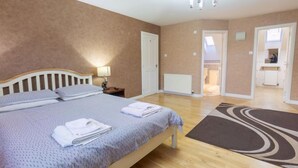 A bedroom with a bed, bedside table, lamp, and a view of a bathroom through an open door. - Evergreen House by Interhome (Inverness)