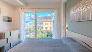Une chambre moderne dotée d’un grand lit, d’une armoire intégrée et d’un balcon offrant une vue sur la montagne.