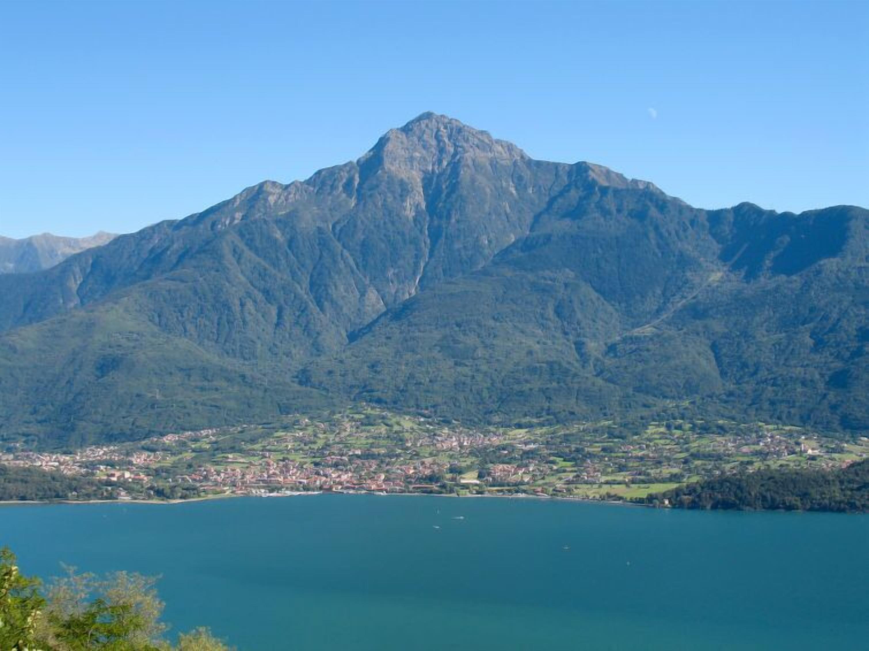 Una montaña con un pueblo a su base y un lago al frente.