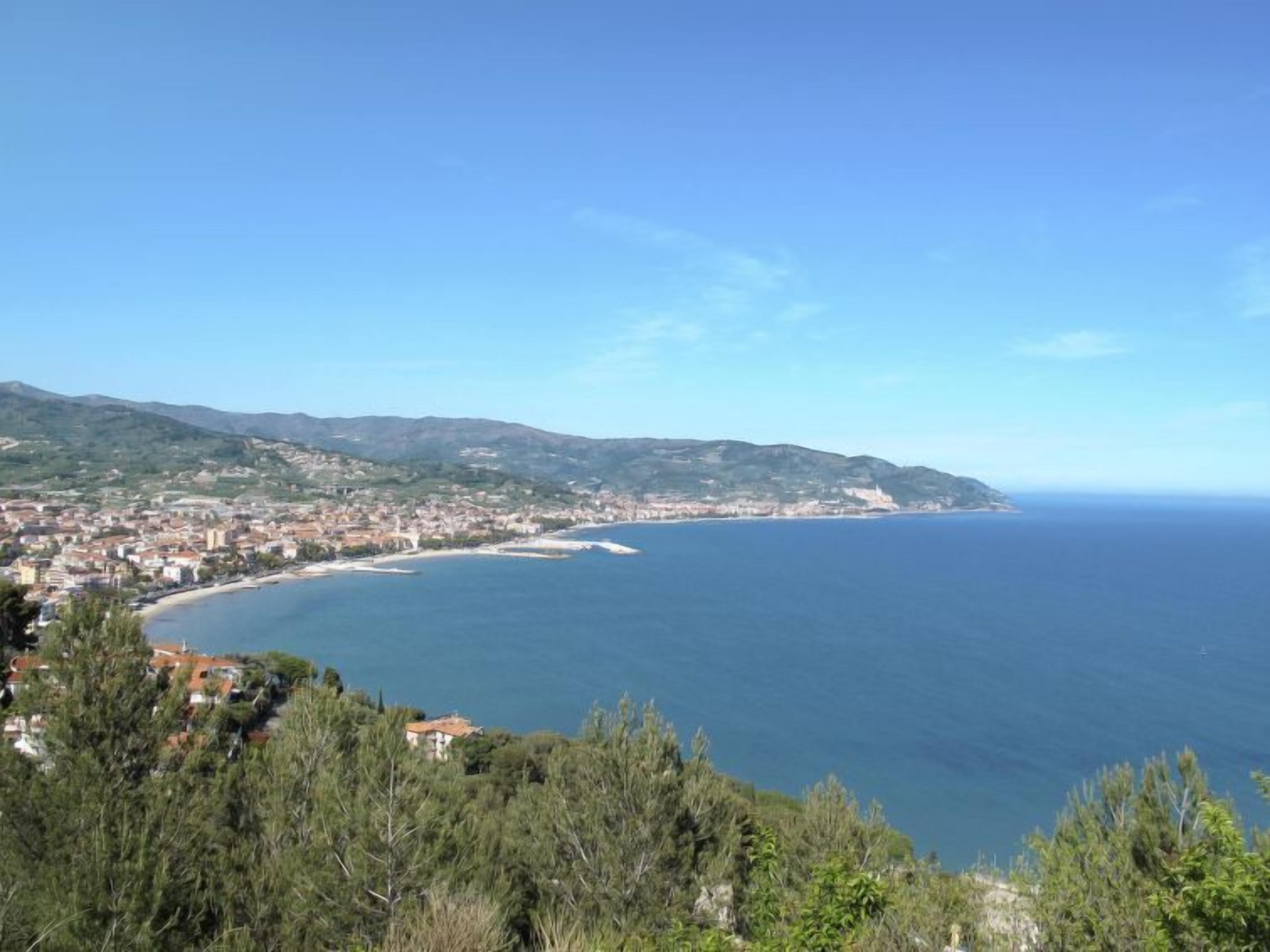 A coastal town with a clear view of the sea and mountains in the background.