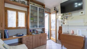 Une pièce confortable avec un lit, un bureau avec des livres, une télévision et un meuble avec des portes en verre.