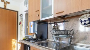 Une cuisine avec des meubles en bois, un évier en acier inoxydable et une bouilloire sur la cuisinière.
