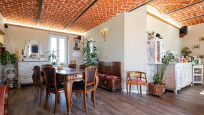 A dining area with a brick ceiling, wooden dining table, and chairs. There are plants and a white cabinet with drawers. - Helix1912 by Interhome (San Damiano d'Asti)