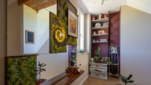 A spacious hallway with wooden flooring, a staircase with a wooden handrail, and a wall decorated with a moss-like texture and a circular design. - Helix1912 by Interhome (San Damiano d'Asti)