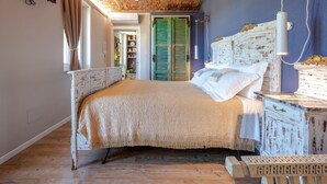 A bedroom with a brick ceiling, a bed with a white headboard, and a wooden dresser. - Helix1912 by Interhome (San Damiano d'Asti)