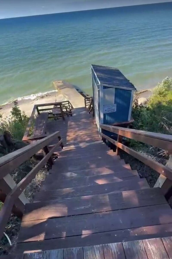 A wooden pathway leading to a beach area with a small blue structure.