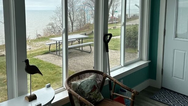 Une pièce avec vue sur le lac, une chaise en osier, une petite table et une porte.