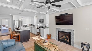 A spacious living area with a fireplace, a kitchen with white cabinets, and a dining area with a table and chairs. - Lady of The Lake (Laconia)