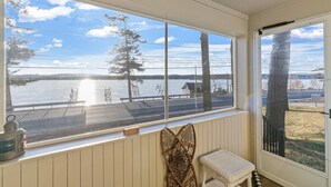 A room with a large window overlooking a lake, a wooden bench, and a lantern on the windowsill. - Lady of The Lake (Laconia)