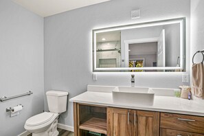 Une salle de bain moderne équipée de toilettes, d’un meuble-lavabo et d’un miroir.