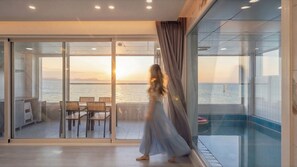 Una stanza con vista sul mare, una porta vetrata, una piscina e un tavolo con sedie.