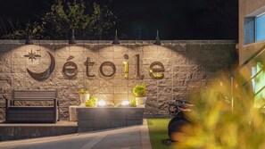 A stone wall with the word 'Jétoile' illuminated, a bench, planters, and a scooter. - Pohang Etoile Poolvilla (Pohang)