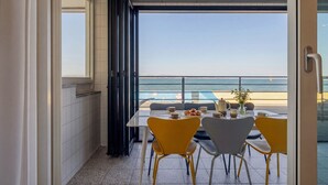 A dining area with a table and chairs, a view of the sea, and a door leading to an outdoor space. - Pohang Etoile Poolvilla (Pohang)