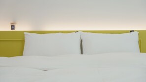 A bed with white bedding, a yellow headboard, and a small nightstand with a lamp. - Pohang Etoile Poolvilla (Pohang)