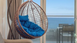 Una poltrona sospesa con cuscino blu in una stanza con vista sul mare.