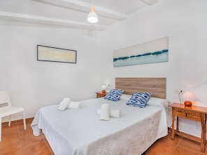 A hotel room with a bed, a chair, a nightstand, a lamp, and a painting on the wall. - Can Camarroja by Sunvillas Mallorca (Pollença)