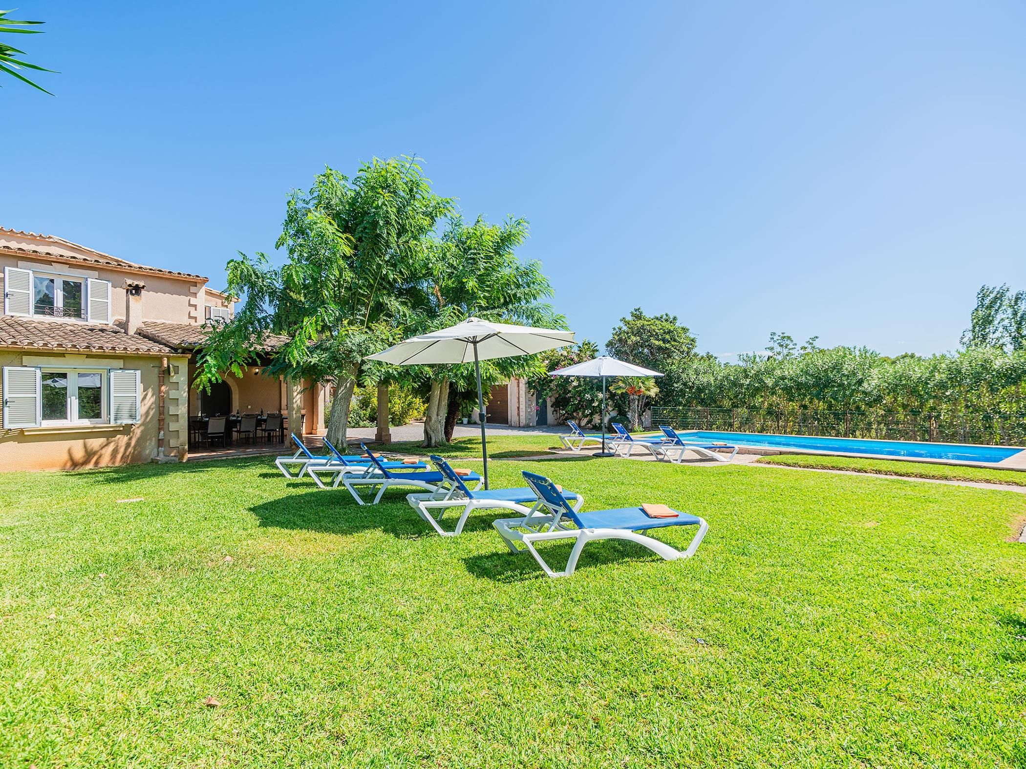 A poolside area with lounge chairs, umbrellas, and a swimming pool.