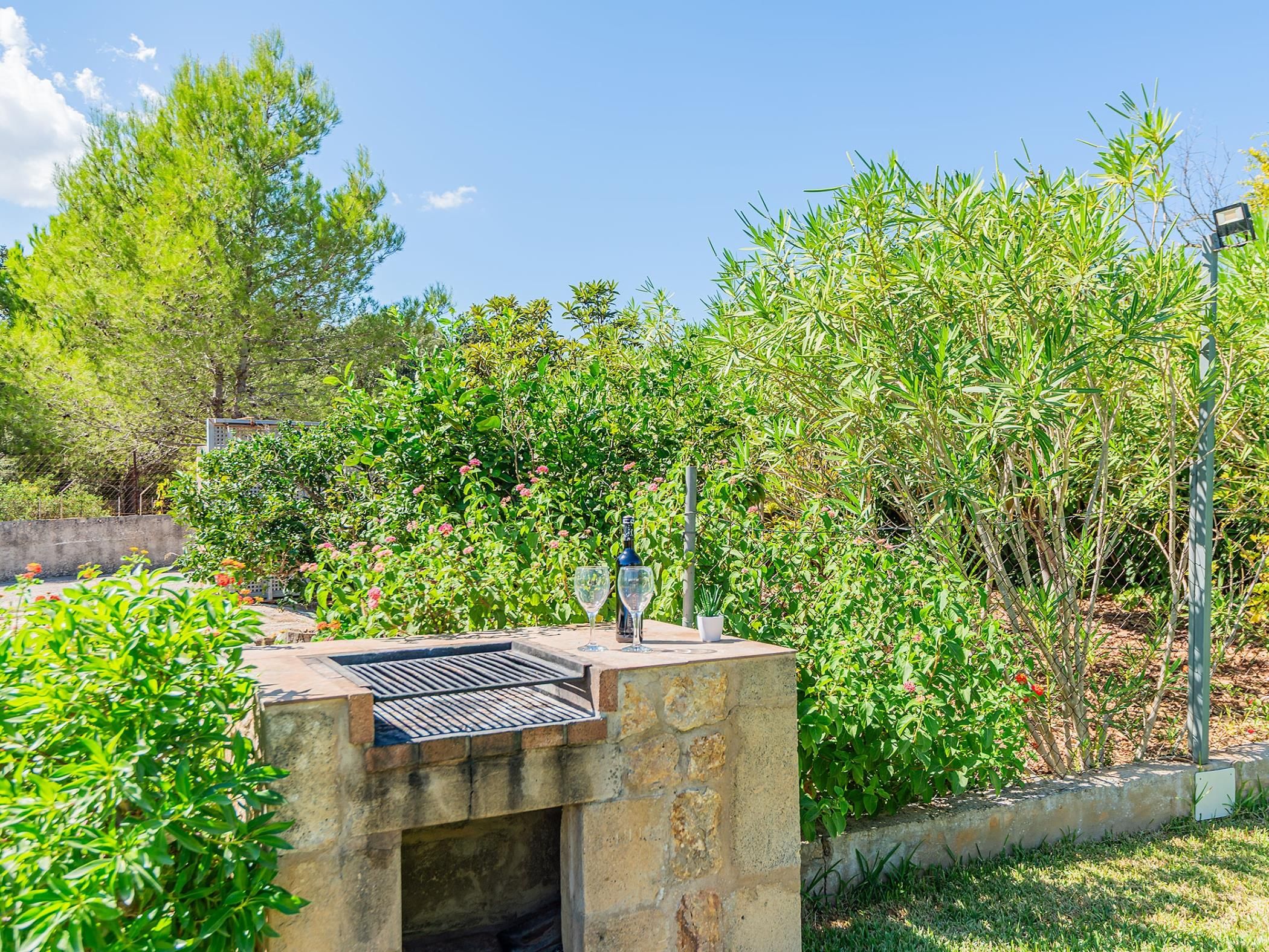 An outdoor barbecue area with a stone structure, two wine glasses, and a bottle.