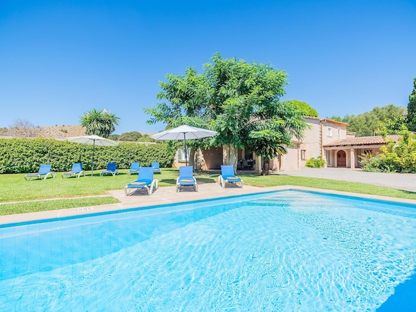 A swimming pool with lounge chairs and umbrellas, surrounded by greenery and a building. - Can Camarroja by Sunvillas Mallorca (Pollença)