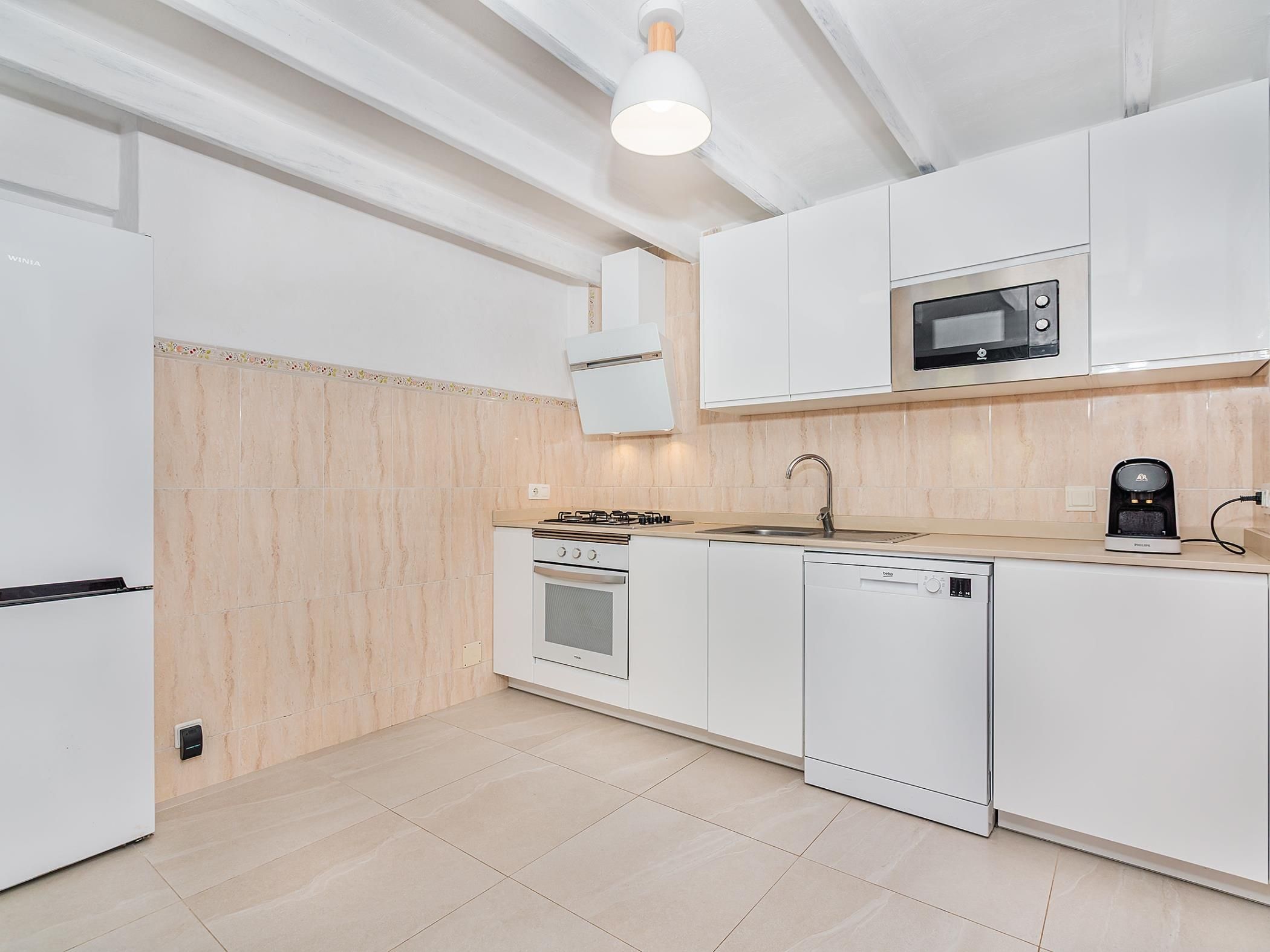 A modern kitchen with white cabinetry, a built-in oven, a dishwasher, and a microwave.