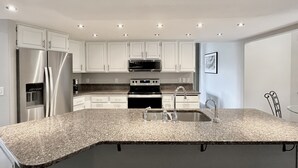 A modern kitchen with white cabinets, stainless steel appliances, a granite countertop, and a stainless steel sink. - Hot tub + Bright and spacious home + 20 min to Ski —> Sleeps 13! (East Wenatchee)