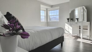 Ein Schlafzimmer mit einem Bett, einem Schminktisch und einem großen Fenster.