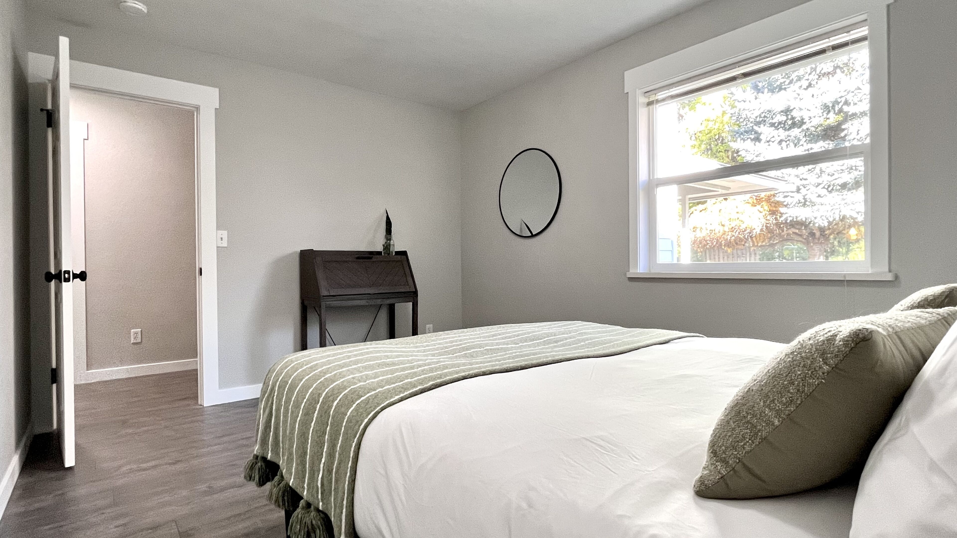 Une chambre à coucher avec un lit, un bureau, une fenêtre et une porte.