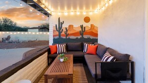 Un espacio al aire libre acogedor con un sofá, almohadones y una mesa de madera.