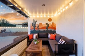 A cozy outdoor seating area with a couch, pillows, and a wooden table.
