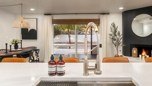 Une cuisine moderne dotée d’un évier en acier inoxydable, d’une hotte intégrée et d’un coin repas avec une table et des chaises.