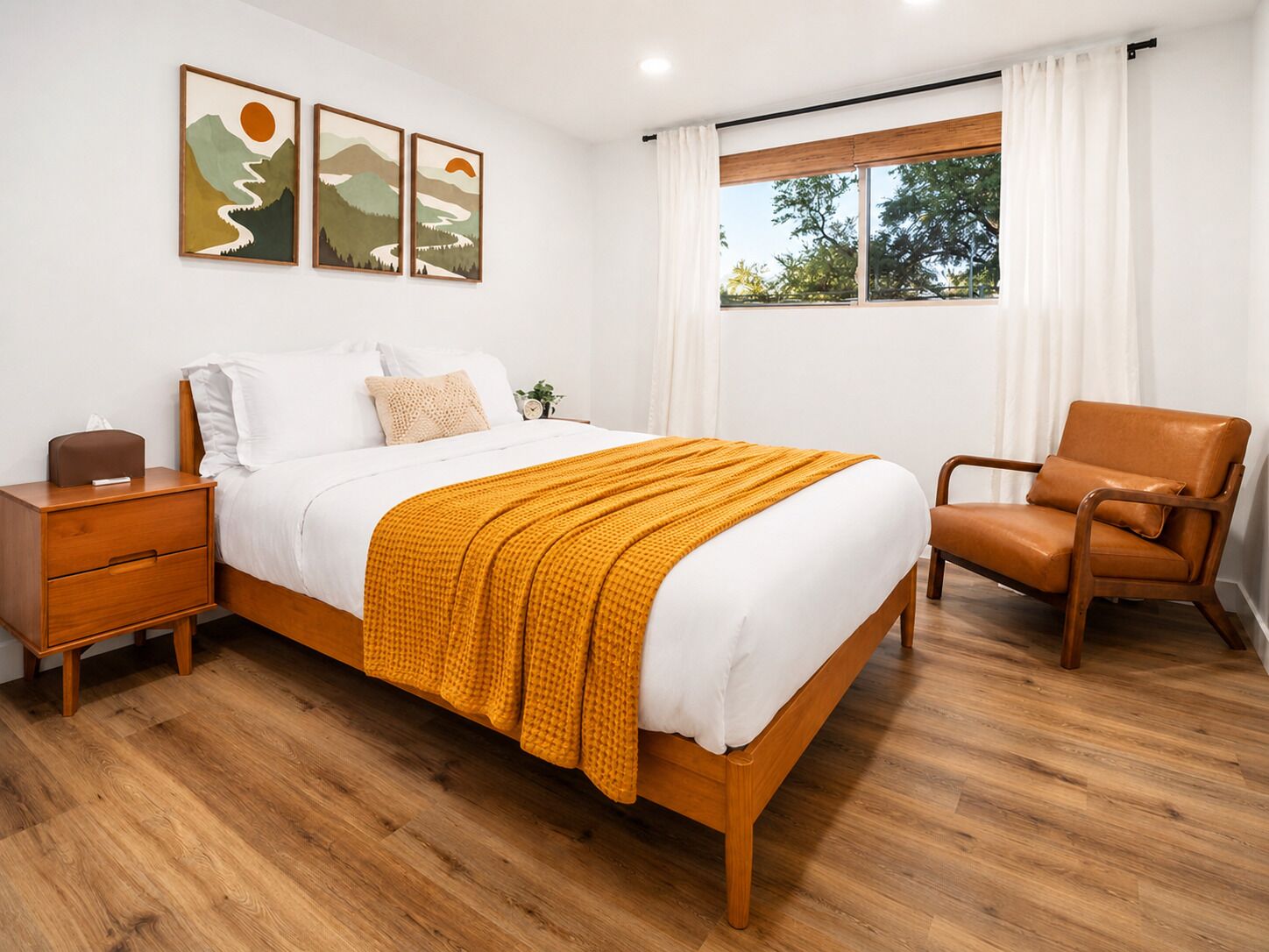 A bedroom with a wooden bed, a nightstand, a chair, and a window with curtains.