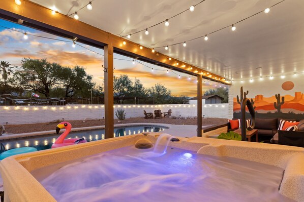 A hot tub with a flamingo float, a pool, outdoor seating, and string lights. - Private Desert Oasis: Pool, HotTub, FirePit, Garage, EV Charger, Near Saguaro (Tucson)