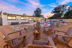 A modern house with a pool, outdoor seating, and a fire pit.