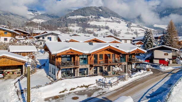 A snow-covered mountain village with wooden buildings, a road, and a mountain in the background. - Luxury apartment with terrace near Kaprun (Piesendorf)