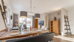 A dining area with a wooden table set for four, a black leather bench, and a wooden cabinet with a ladder. - Luxury apartment with terrace near Kaprun (Piesendorf)