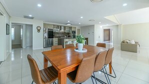 Una cucina moderna con elettrodomestici in acciaio inossidabile, un'area pranzo con tavolo e sedie in legno, e un soggiorno con divano.