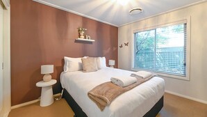 Una camera da letto con un letto grande, comodini, una finestra con tende e uno scaffale a parete con un vaso.