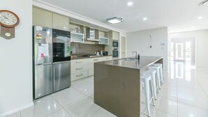 Una cucina moderna con elettrodomestici in acciaio inossidabile, un'isola centrale e sgabelli da bar.