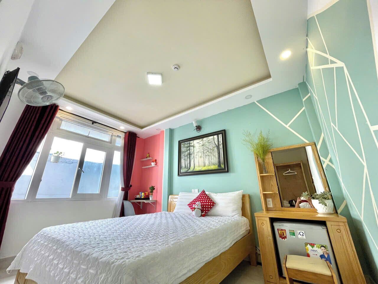 A bedroom with a bed, a desk, a chair, a window, and a ceiling fan.