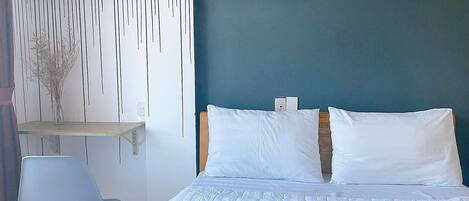 A bedroom with a bed, a chair, a shelf with decorative items, and a wall with a 'LOVE' sign.