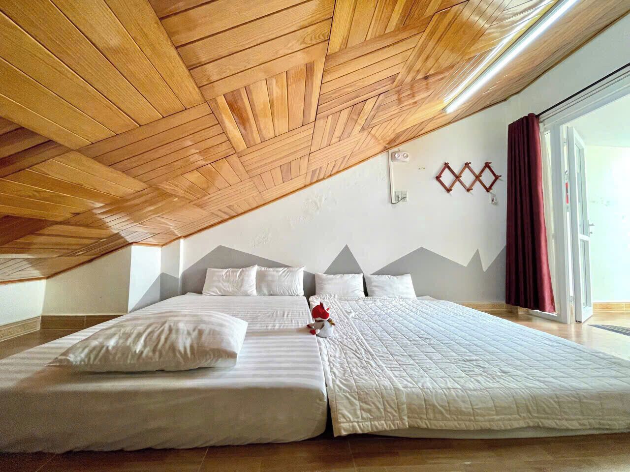 Een slaapkamer met een schuine kap, een groot bed met wit beddengoed en een klein decoratief item op het bed.