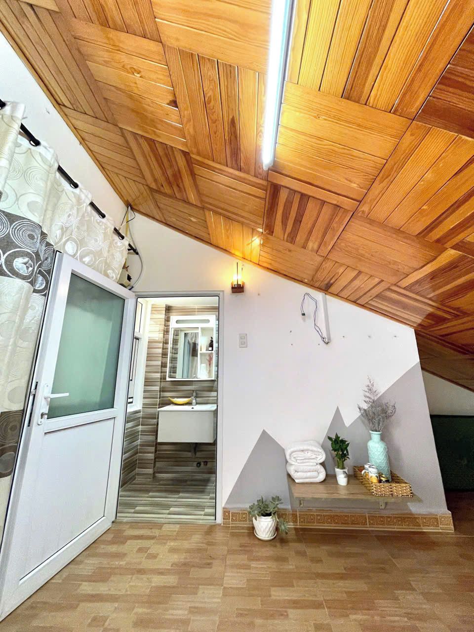 Une salle de bain moderne avec un plafond en bois, une cabine de douche en verre, un lavabo blanc et un miroir.