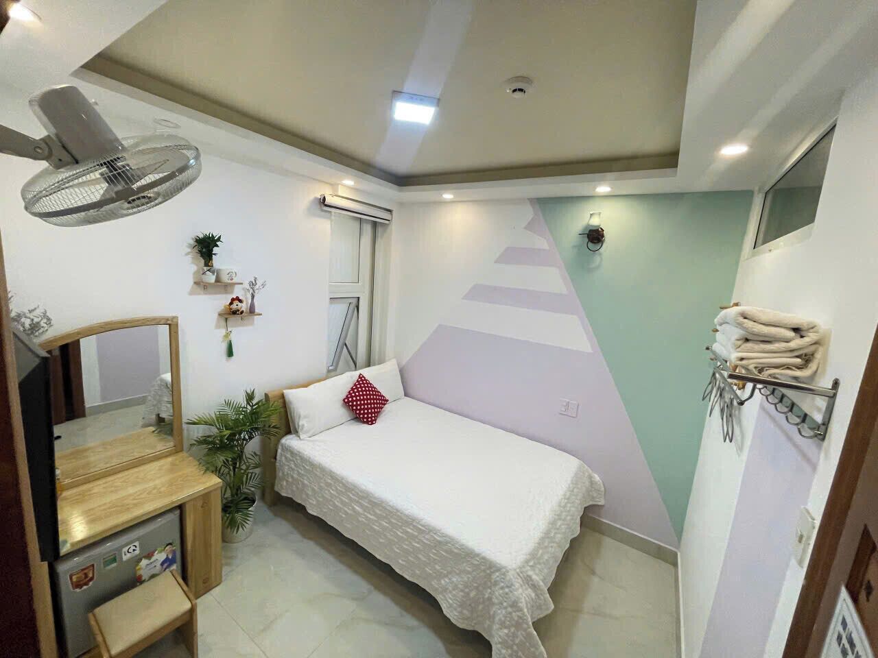 A bedroom with a bed, a TV, a mirror, a fan, and a wall-mounted air conditioner.
