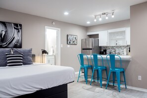 A modern bedroom with a large bed, a nightstand, and a desk with chairs. - Montrose Chelsea Studio! Medical Center 10 (Houston)