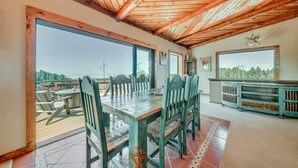 Un vaste espace dédié à la salle à manger, avec une table et des chaises en bois, de grandes fenêtres et une vue sur l’extérieur.