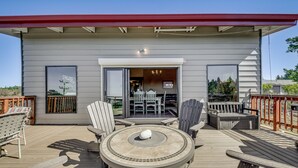 Une terrasse dotée d’une table ronde, de chaises et d’un foyer intégré.