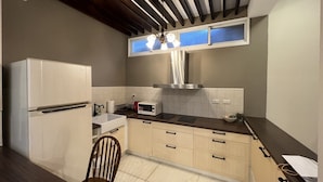 A compact kitchen with a built-in microwave, a stainless steel range hood, and a window above the sink. - Anping Ease (Tainan)