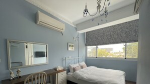 A bedroom with a bed, a desk, a chair, a dresser, a mirror, and a window with a view. - Anping Ease (Tainan)