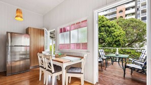 A modern kitchen with a stainless steel refrigerator, a dining table with chairs, and a large window with patterned glass. - Tranquil 3-Bed Family Home with Spacious Backyard (Nundah)