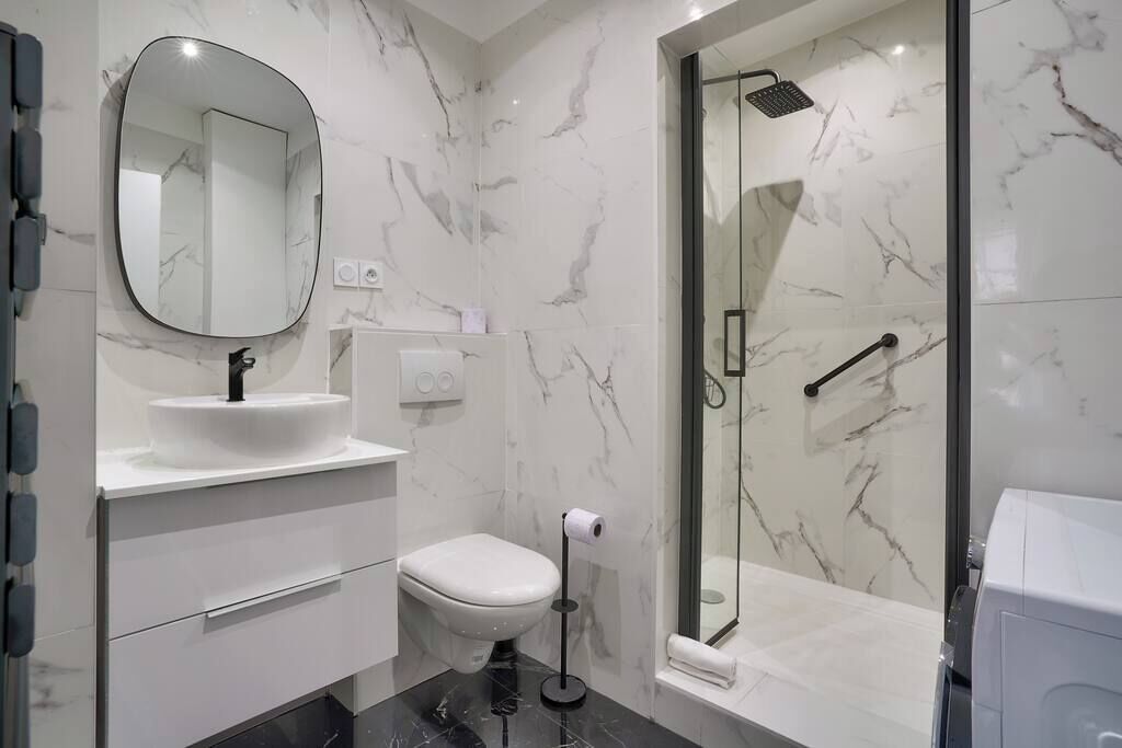 Ein modernes Badezimmer mit Marmorwaschbecken, Toilette und Dusche.